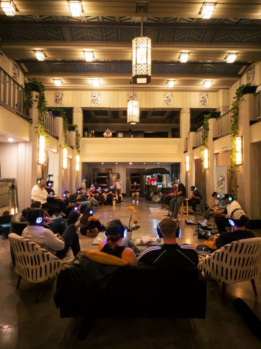 Audience in glowing blue headphones seated around the HEXI building lobby