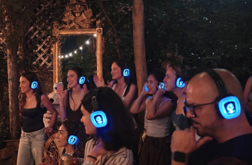 Row of guests smiling in glowing blue LED headphones