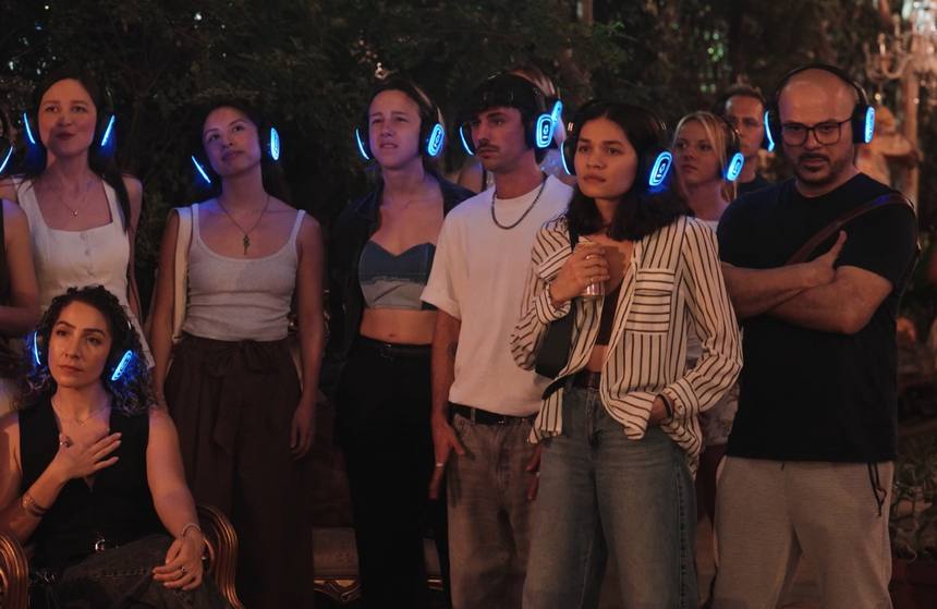 Guests in headphones watching the show in the candlelit garden